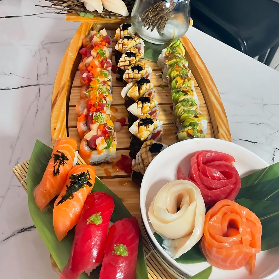 A large sushi boat filled with various colorful sushi rolls, nigiri, and sashimi roses.