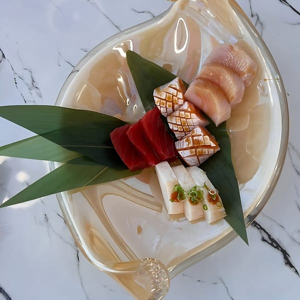 Assortment of fresh sashimi, including tuna, salmon, and white fish, on a decorative plate.